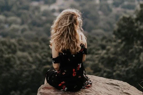 woman sitting on cliff