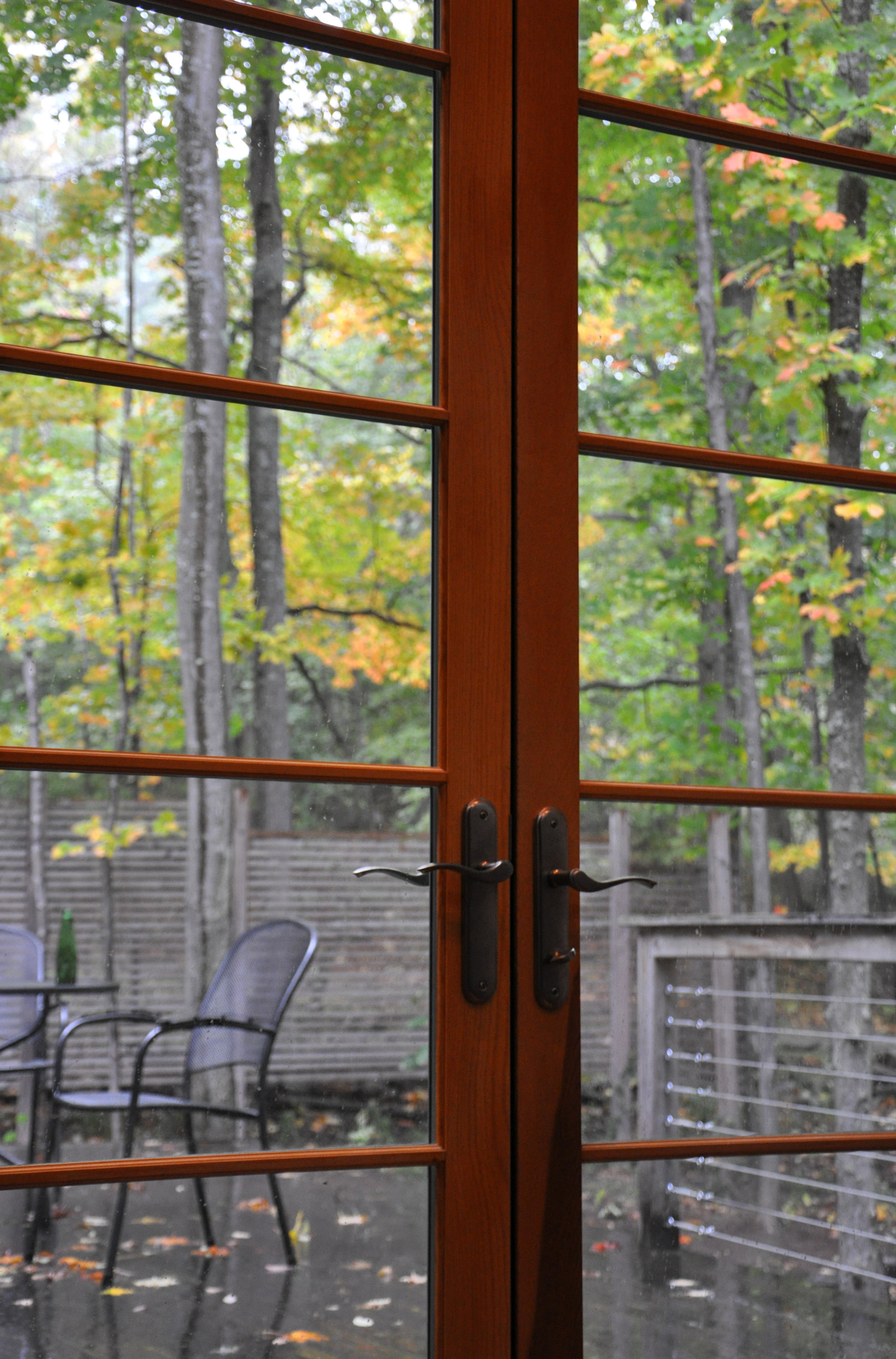 Autumn view through french doors to large patio with outdoor seating in a rural, wood-frame, energy-efficient vacation home