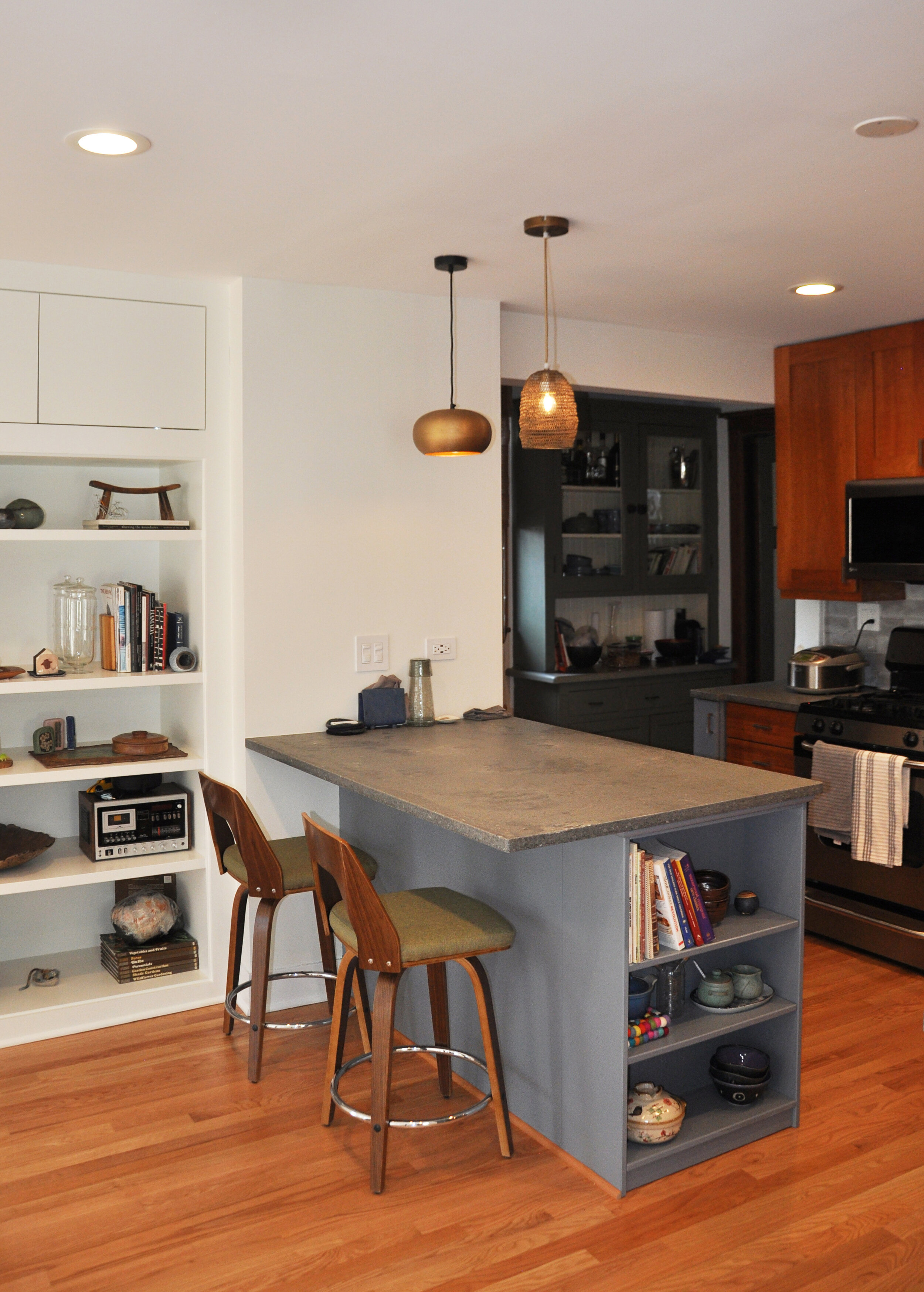 renovated kitchen with built-in bookshelf, hardwood floors, kitchen counter with stool seating