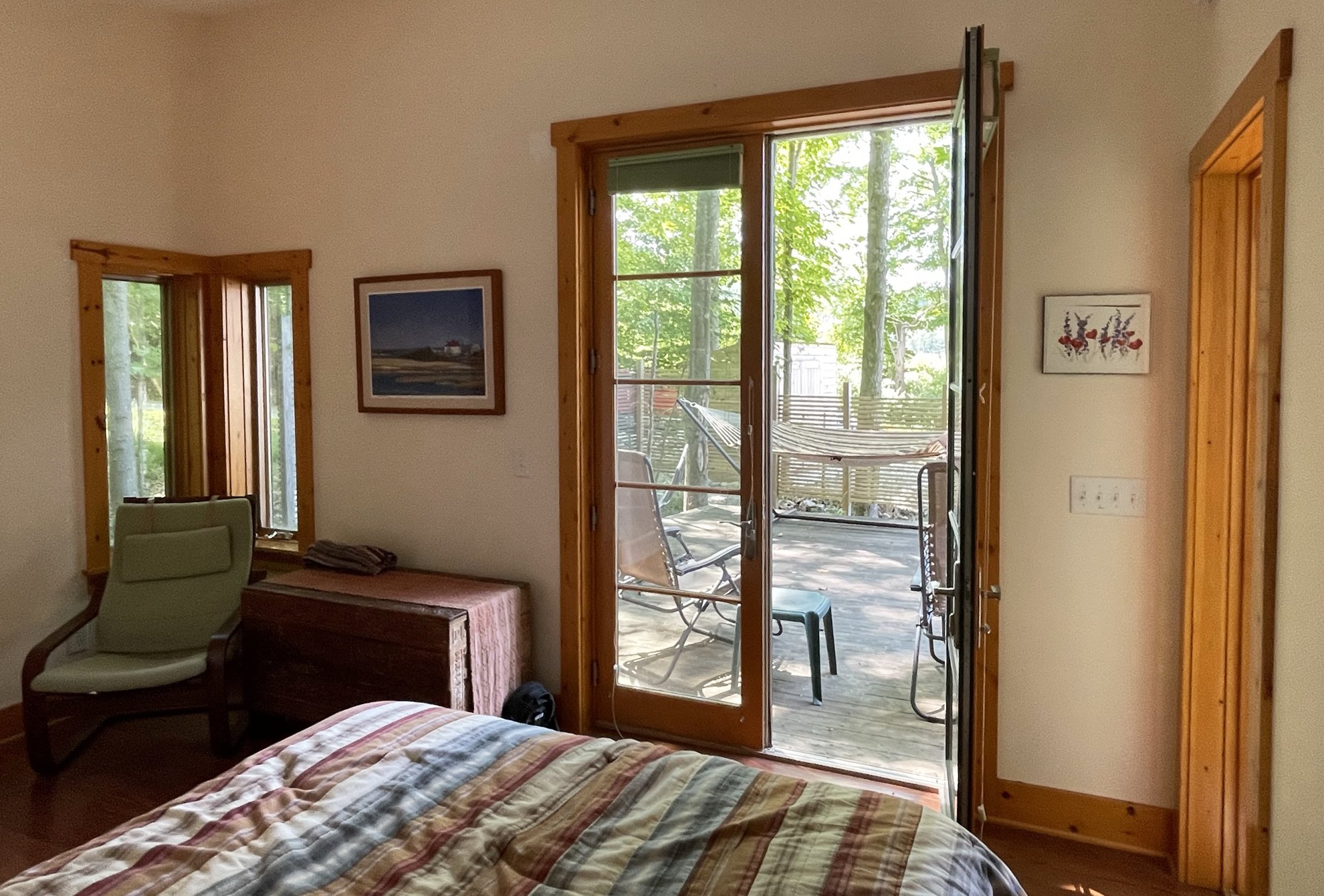 Primary bedroom suite with french doors open to patio in rural, wood-frame, energy-efficient vacation home 