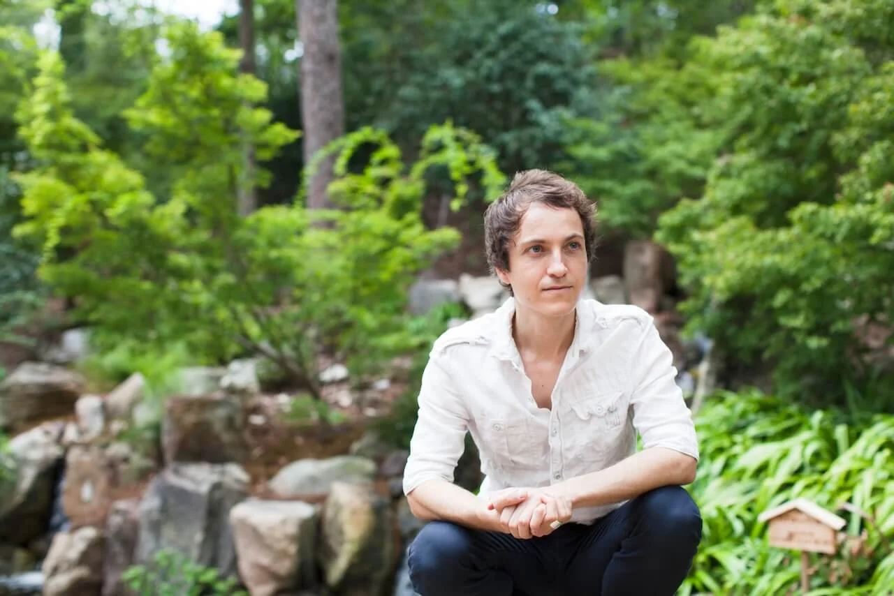 Simon Spire crouching in a rock garden looking to the side.