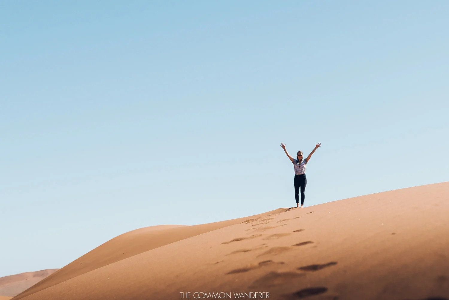 A woman stands atop a sand dune in Sossusvlei, Namibia - The Common Wanderer
