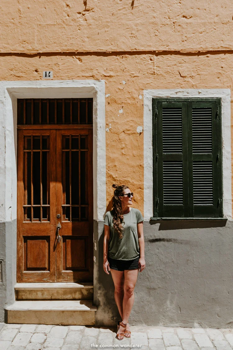 a woman stands in front of a colourful wall, Ciutadella, Menorca