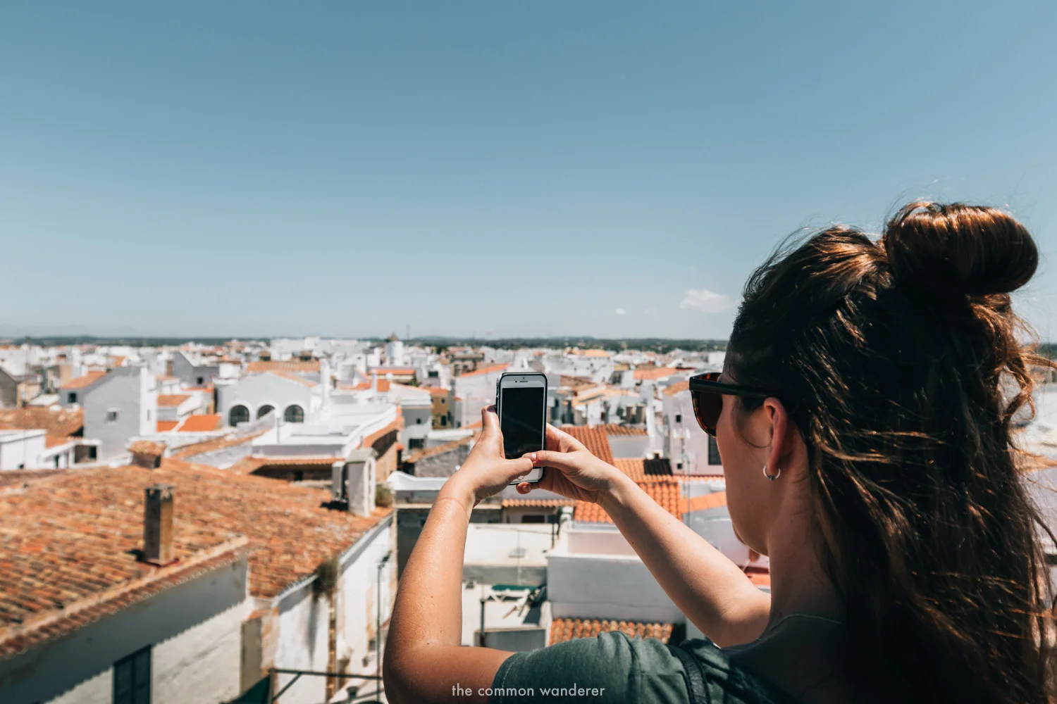 A woman takes a photo on her smartphone overlooking Ciutdella, Menorca