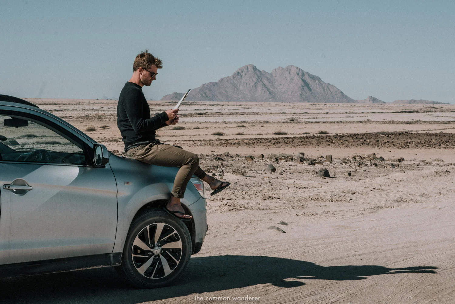 A man reads a map with Spitzkoppe mountain range in the background, Namibia road trip itinerary