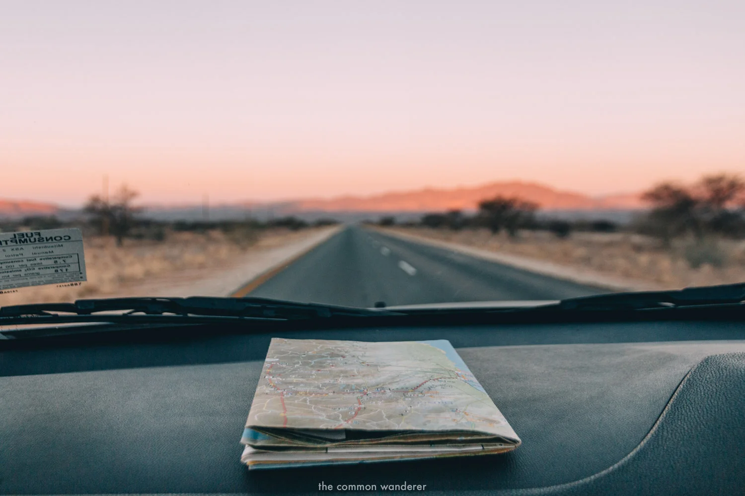 A road map on the dashboard of a car, sun setting in the background - Namibia