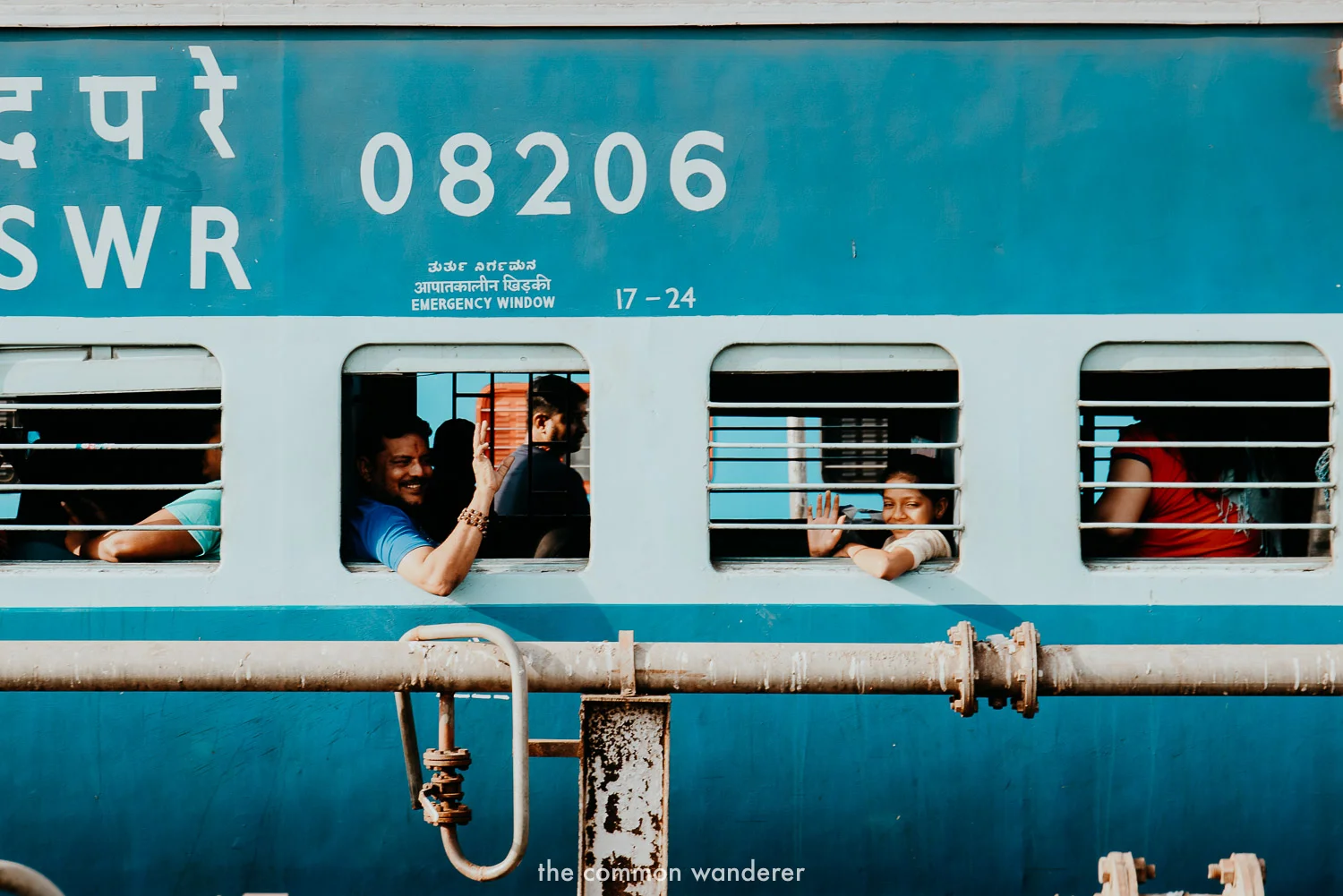 A family smile out the window of a train in India