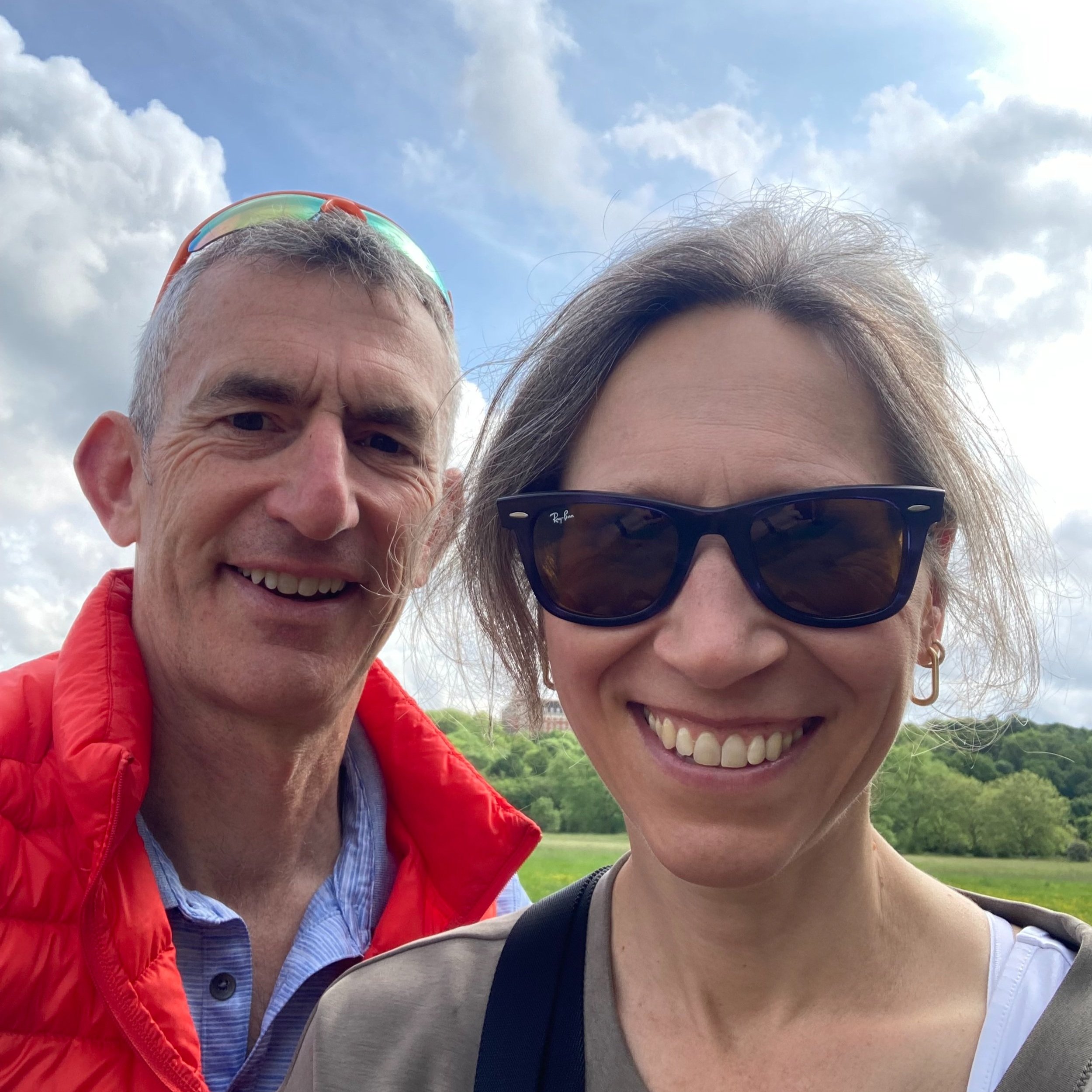 A photo of Caroline and her husband, out for one of their weekly walk and talks. They are by the river and both smiling at the camera.