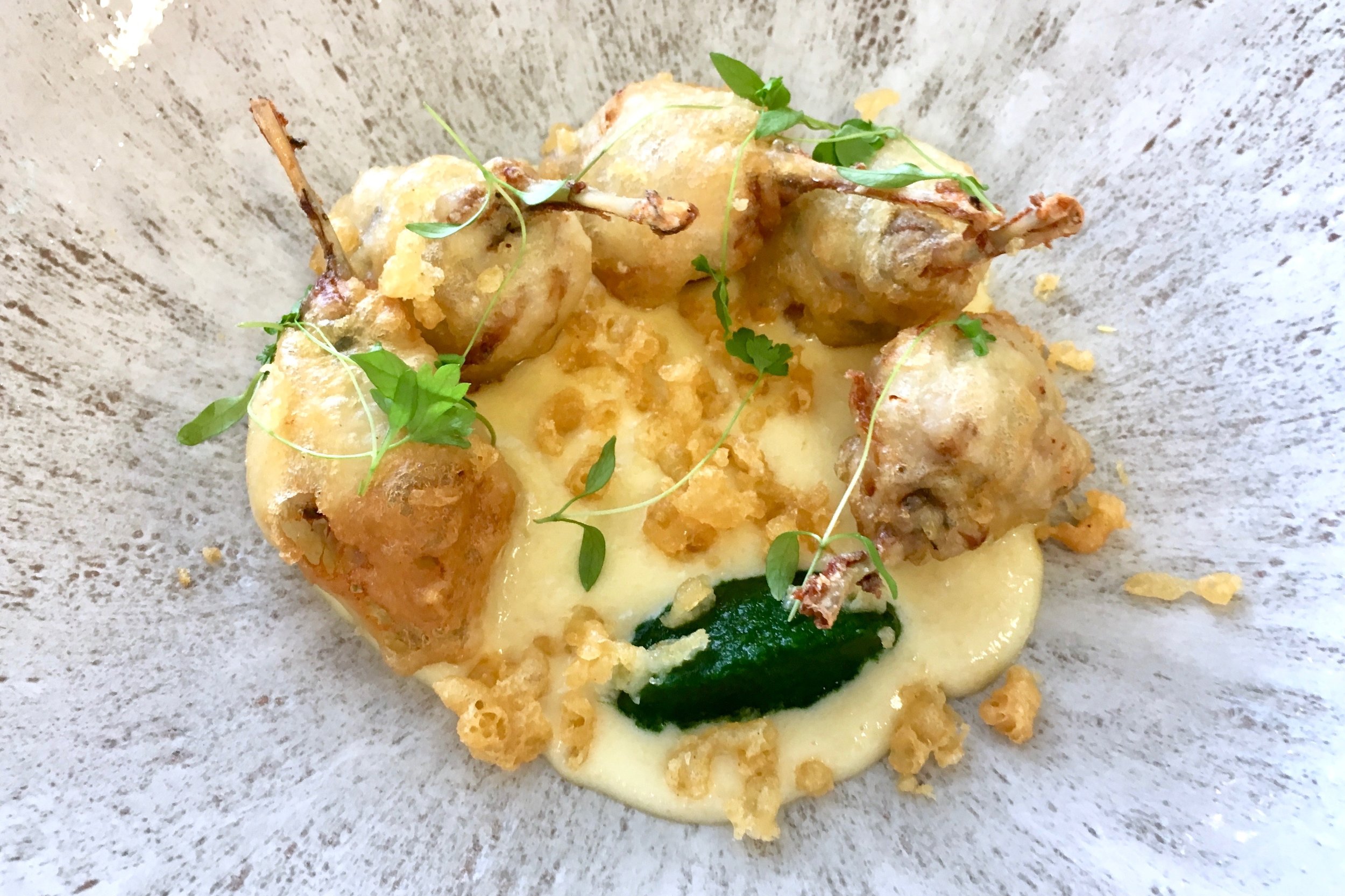 Frogs legs lollipops with garlic cream and parsley coulis