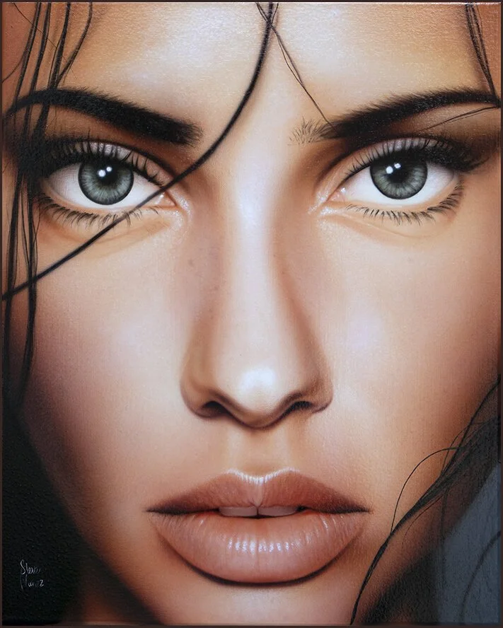 Close-up of a woman's face with striking gray eyes, dark hair, and full lips.