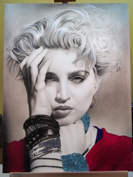 Close-up of a black and white portrait of a woman with short, curly platinum blonde hair, wearing a red top and jewelry, with her hand touching her face.