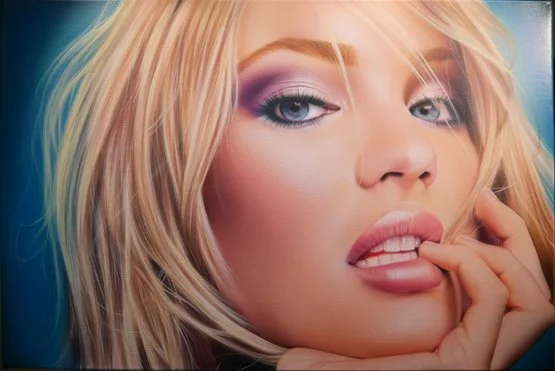 Close-up of a woman with blonde hair, purple eye makeup, and pink lipstick, biting her finger.