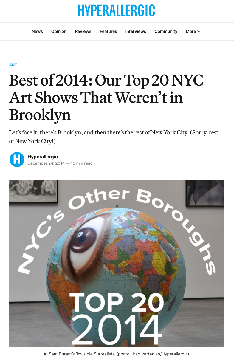 Photograph of a globe with a large eye image on it, surrounded by the text 'NYC's Other Boroughs TOP 20 2014'. Background shows framed artwork on the wall.