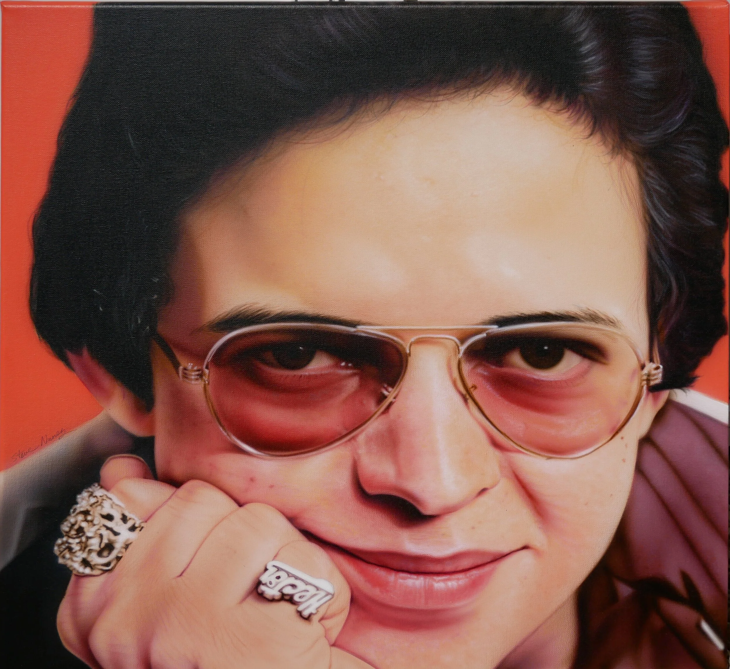 Close-up of a person wearing sunglasses, showing part of their face, hair, and jewelry, with a red background.