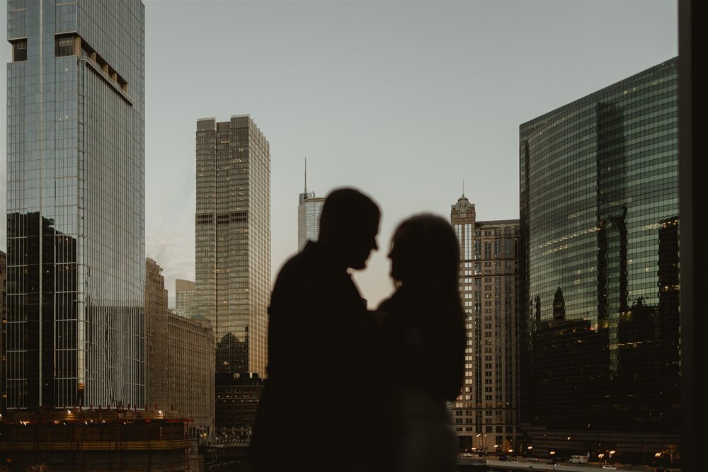 silhouette of couple in front of chicago city building and chicago city skyline. photo by chicago wedding photographers, the gernands photography.