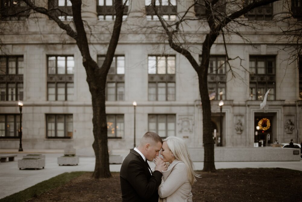 Man in black suit and woman in white dress, posing in front of chicago city hall before their wedding. photo by chicago wedding photographers The Gernands Photography