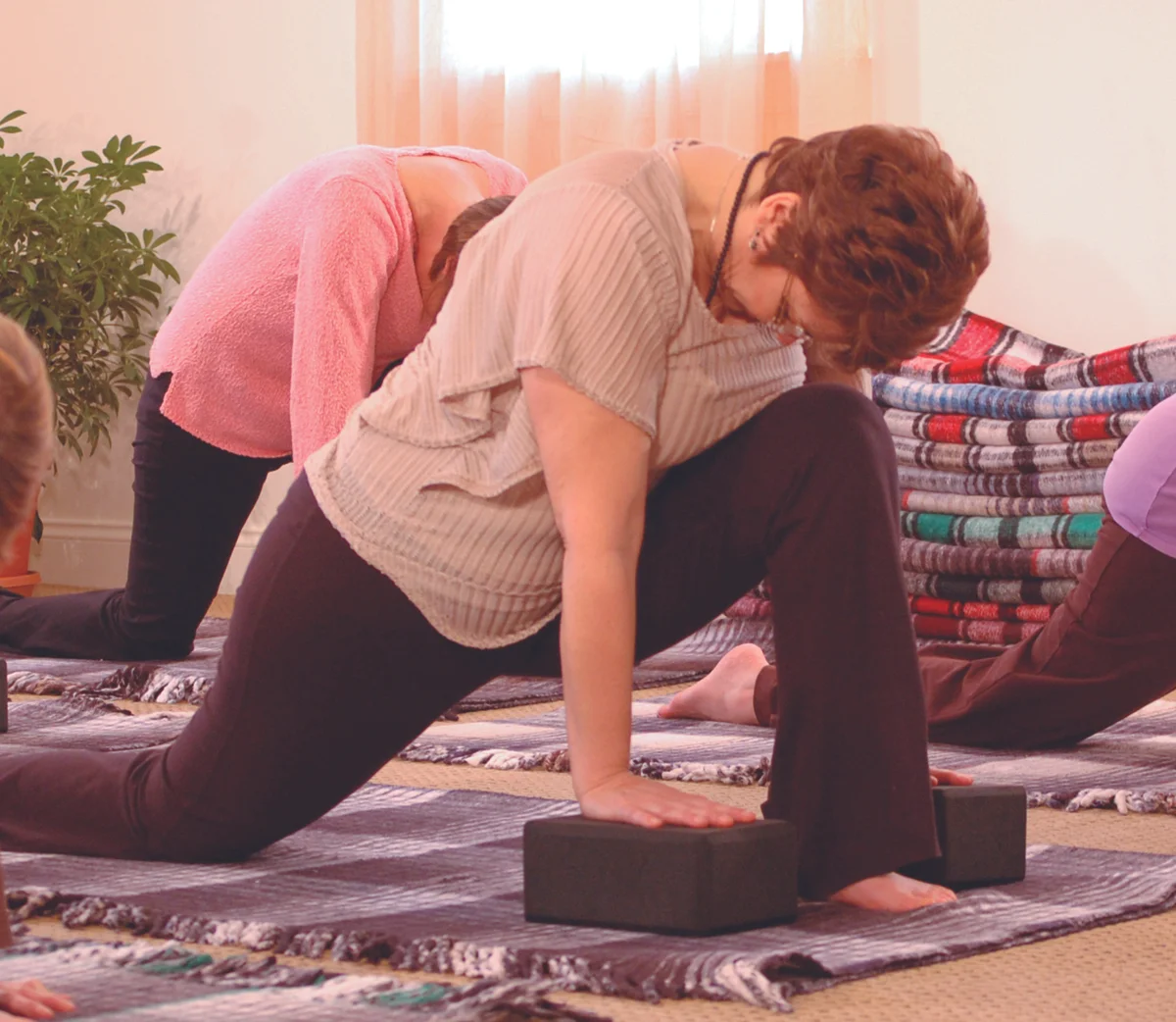 Class using blankets and blocks for support in Anjaneyasana (Lunge), an extension pose for the spine, which releases tight muscles along the spine at the waist. Photo used courtesy of Svaroopa® Vidya Ashram.