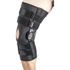 A black knee brace with straps and hinges is worn on a person’s leg for added support and stability.