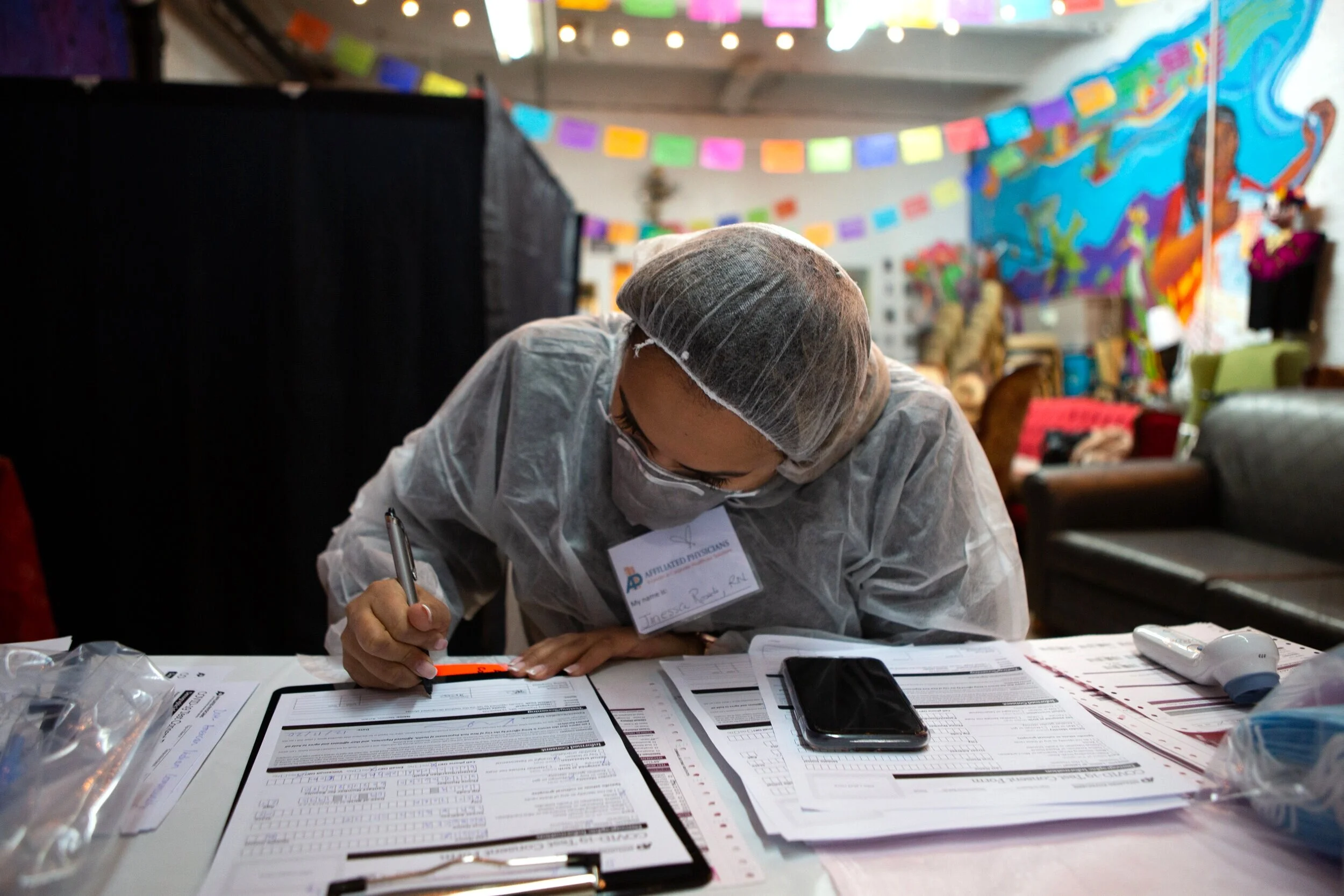 Janessa, an Associated Physicians nurse, processes registration paperwork for walk-in COVID testing and flu vaccine patients.