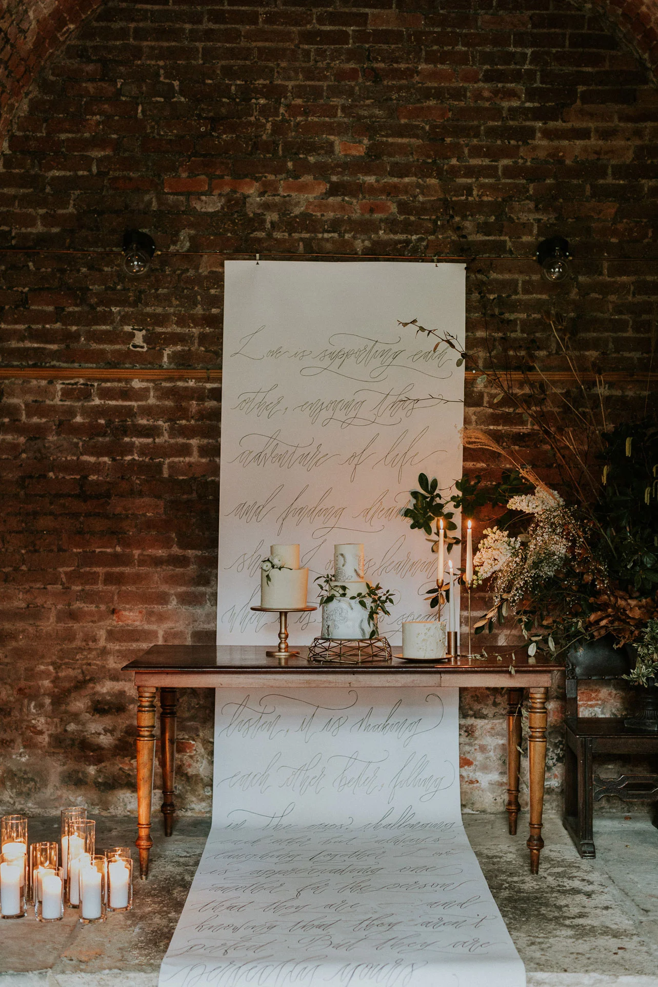 Hand calligraphed wedding banner for a romantic cloister wedding. Here acting as a backdrop for the stunning wedding cake display.