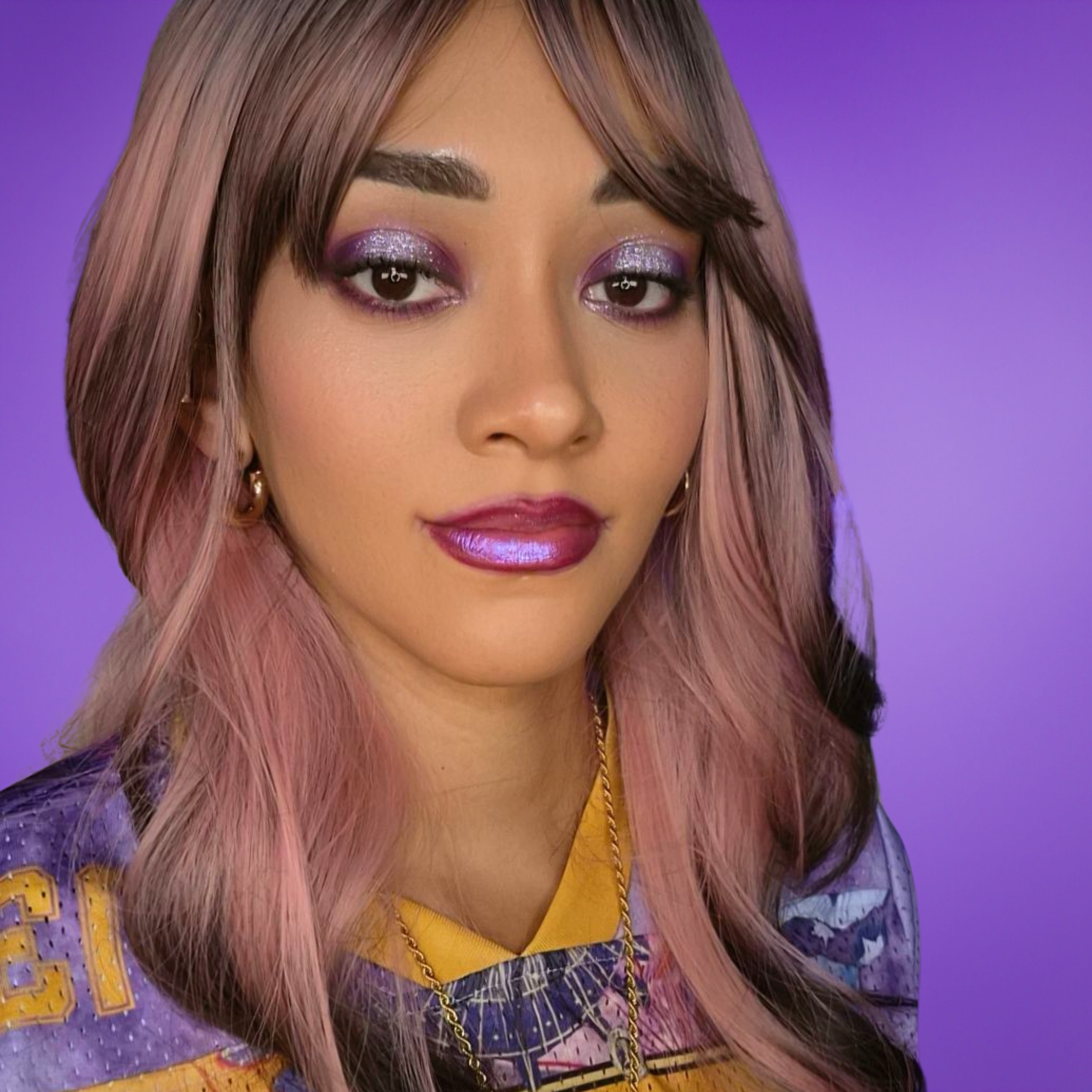 High Priestess Demari, spiritual advisor and psychic reader with long pink and brown hair, purple make-up. Wearing a cat tarot card jersey top, gold ankh necklace and gold hoop earrings.