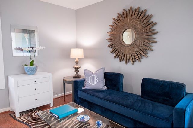 This little office nook in a master bedroom was fun! We went a little more modern/eclectic with this space with the navy blue sofa, acrylic coffee table, zebra rug, and the fun mirror. #interiordesign #officedesign #modern #eclectic #zebrarug #acryli
