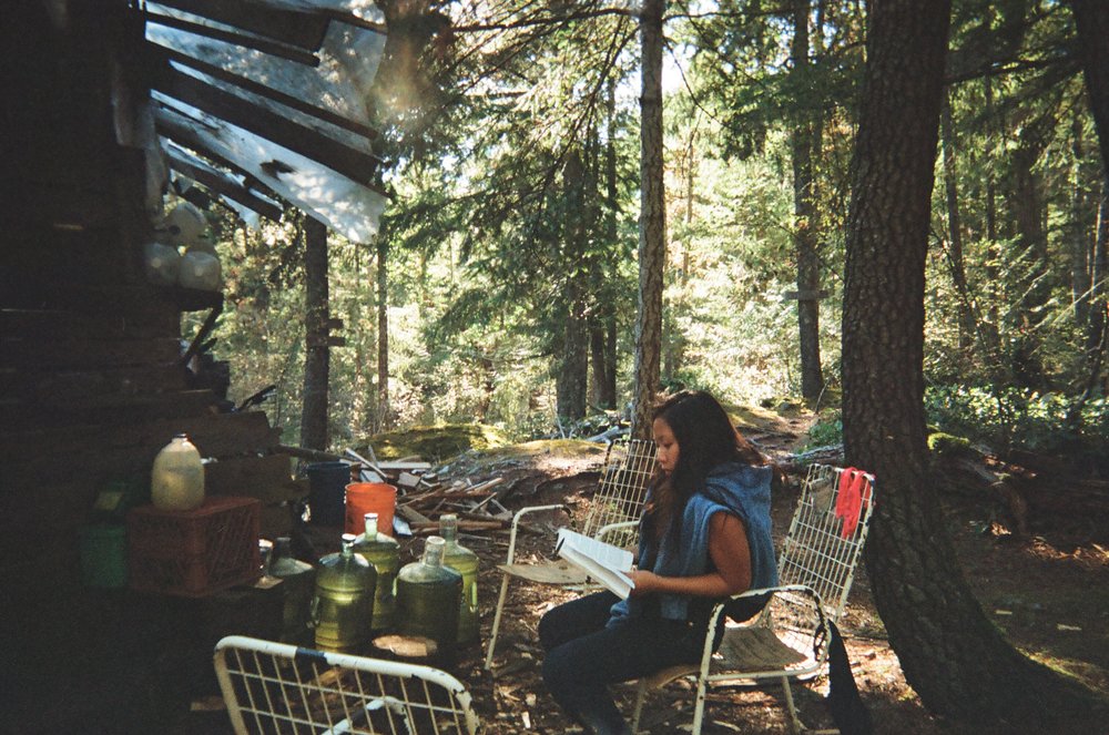 Cherry reading at the yurt, by jugs of collected rainwater, snapped with my Konica on 35mm film.