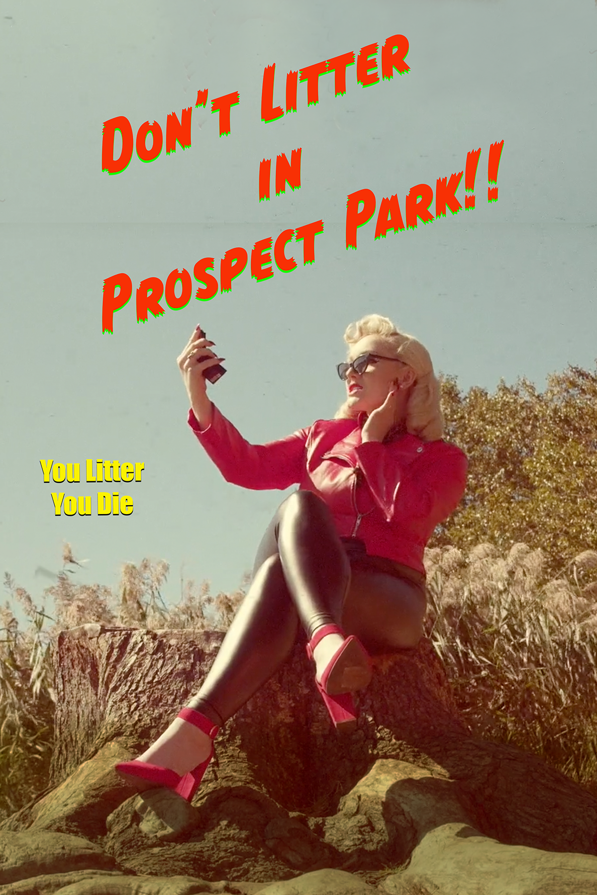 A woman with blonde hair, sunglasses, and red clothing sitting on a fallen tree, taking a selfie outdoors with a sign that says 'Don't litter in Prospect Park!!' in bold red and green letters, and a smaller sign that reads 'You Litter You Die' in yellow text.