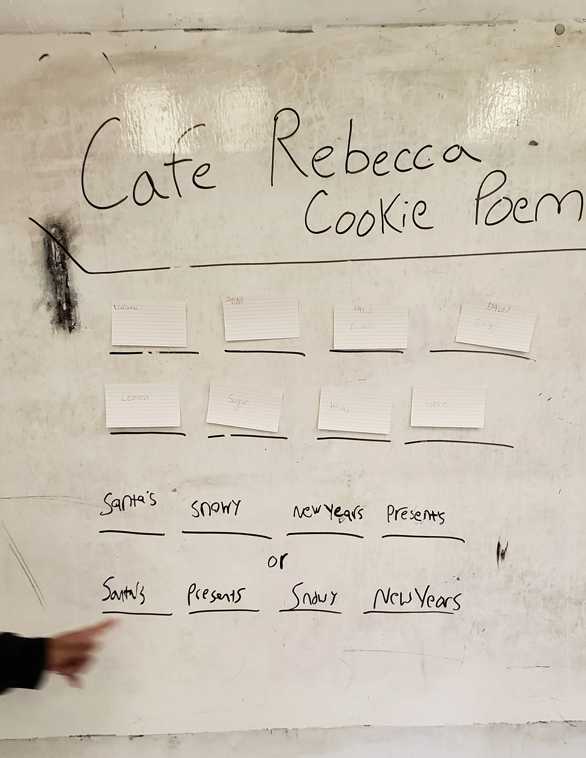 School white board set up with sixteen blank, black lines in a four by four grid. On these blank lines now are notecards with individual words and some hand written words