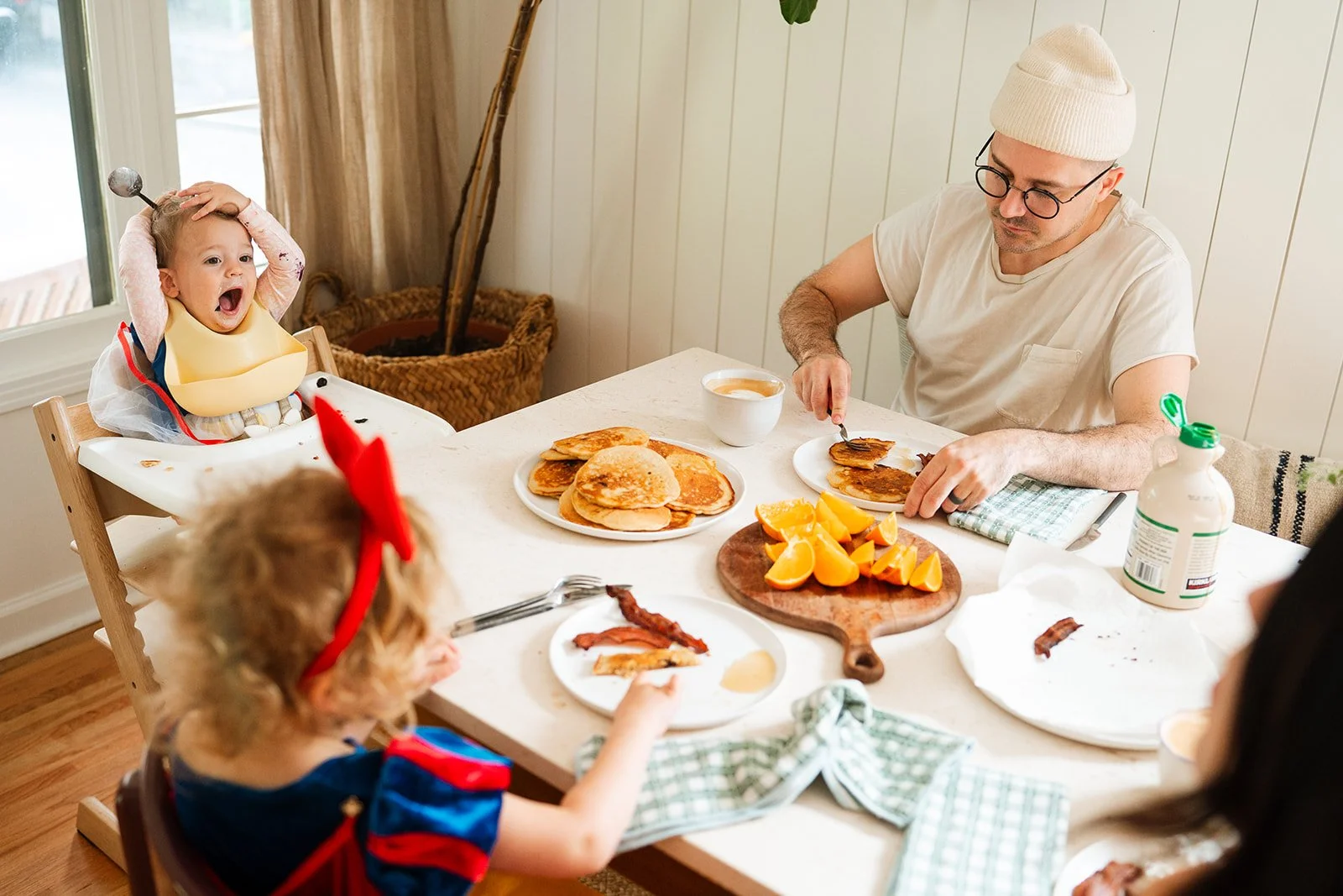 family eating at table with little girls hands on her head and mouth open wide