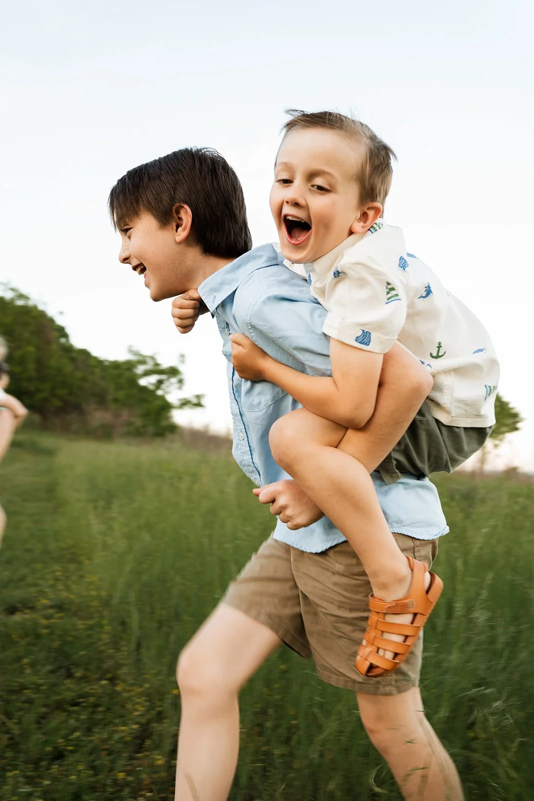 10 year old boy giving his 5 year old brother a piggy back ride while running and both smiling