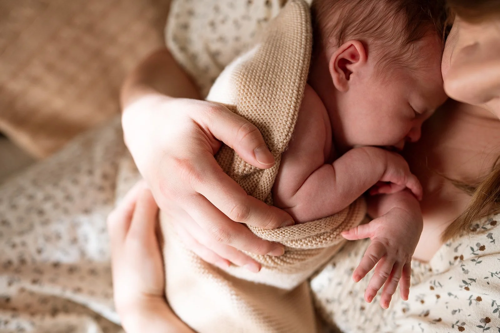 Close up photo of mother holding her sleeping newborn in her arms