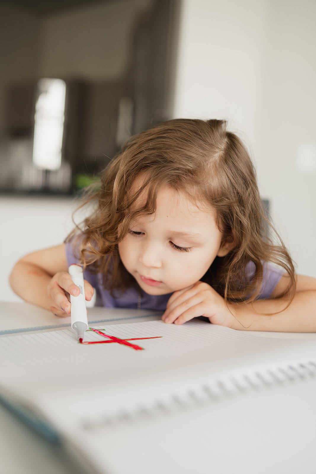 Little girl sitting at a table drawing an airplane