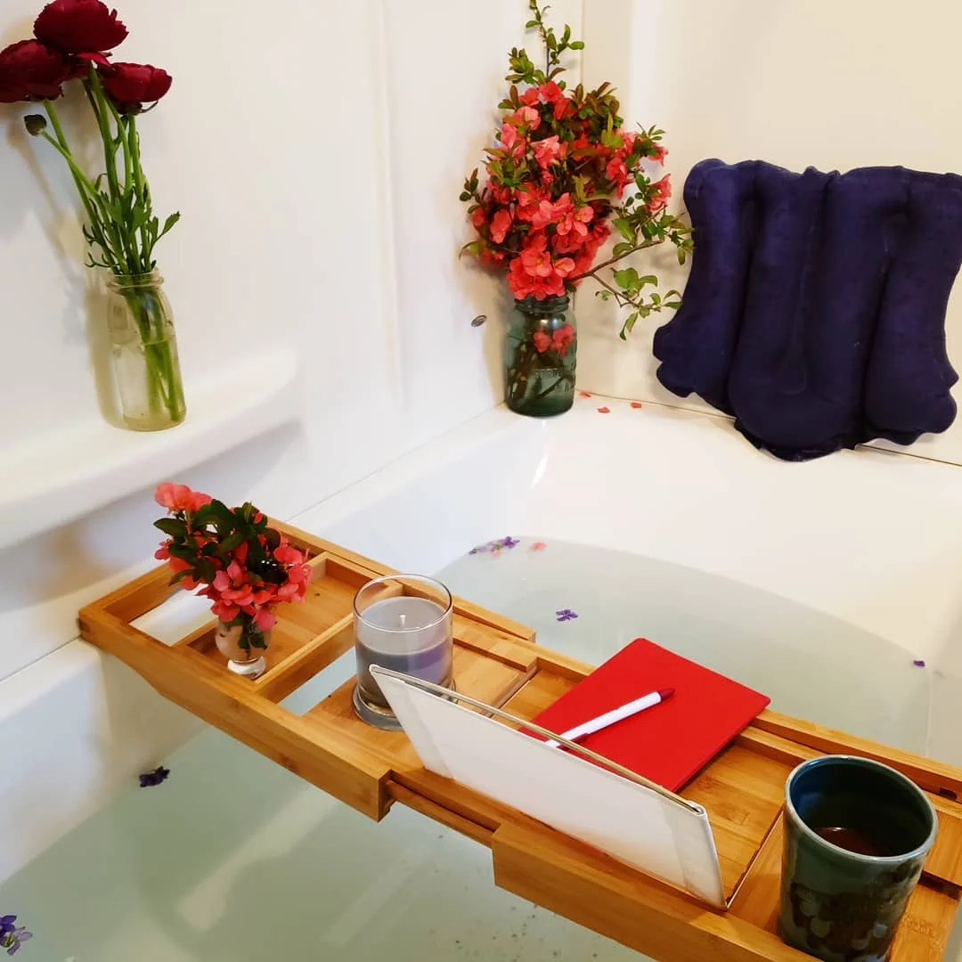 This is my personal bath setup- complete with caddy, pillow, bath salts dissolving in the tub, my candle ready to light, flowers & a beverage… oh yeah, my journal, too.