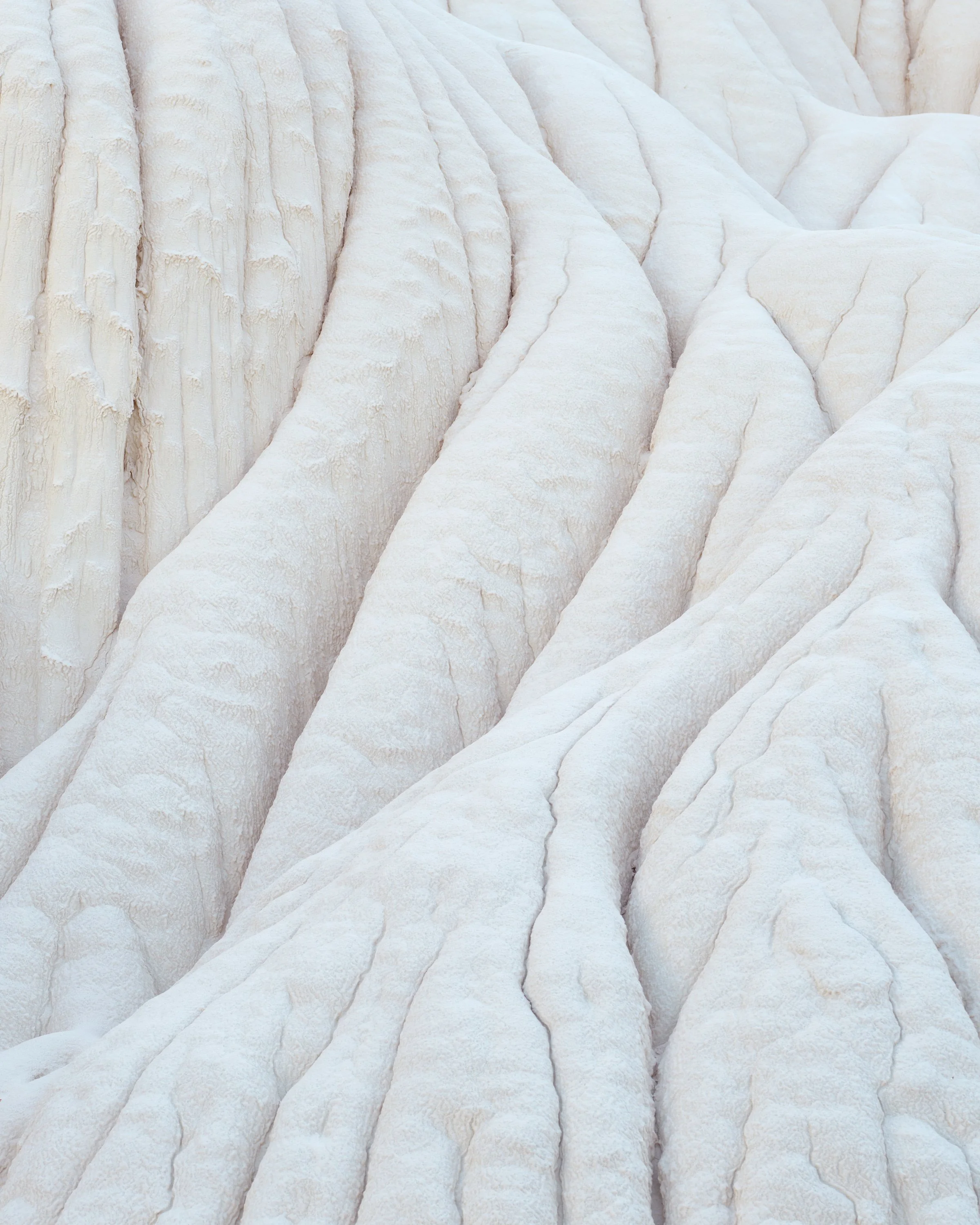 Close-up of white sedimentary rock formations with layered, wavy textures.