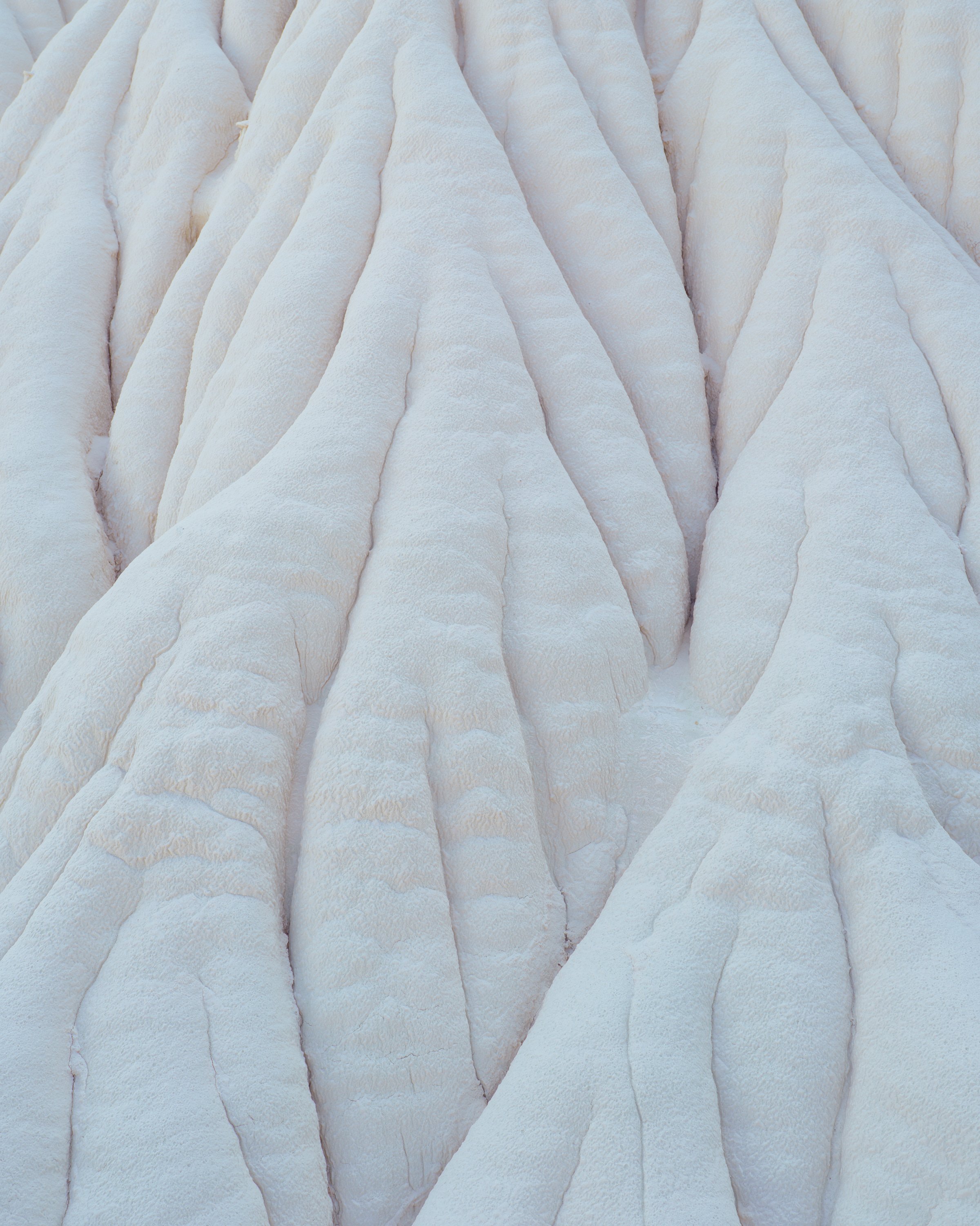 Close-up image of layered snow formations, showing ridges and crevices with a white, icy texture.