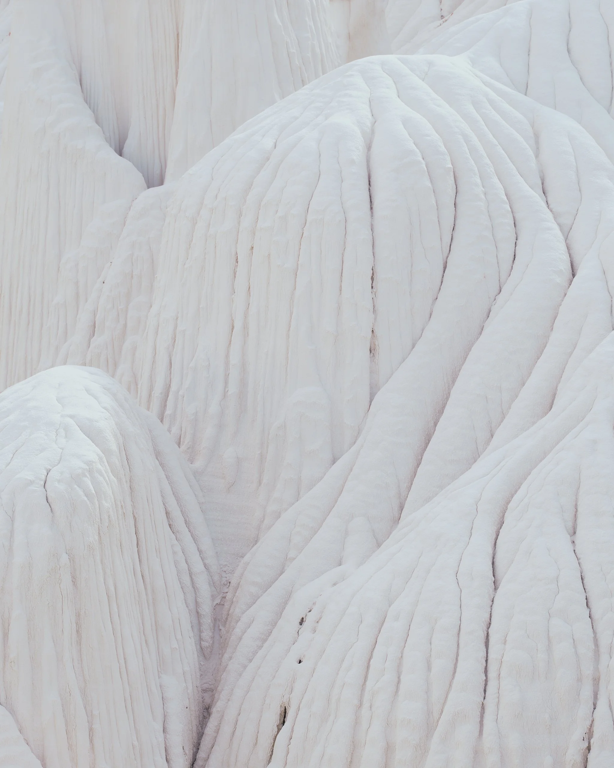 Close-up of white, layered, rock formations with smooth, curved surfaces.
