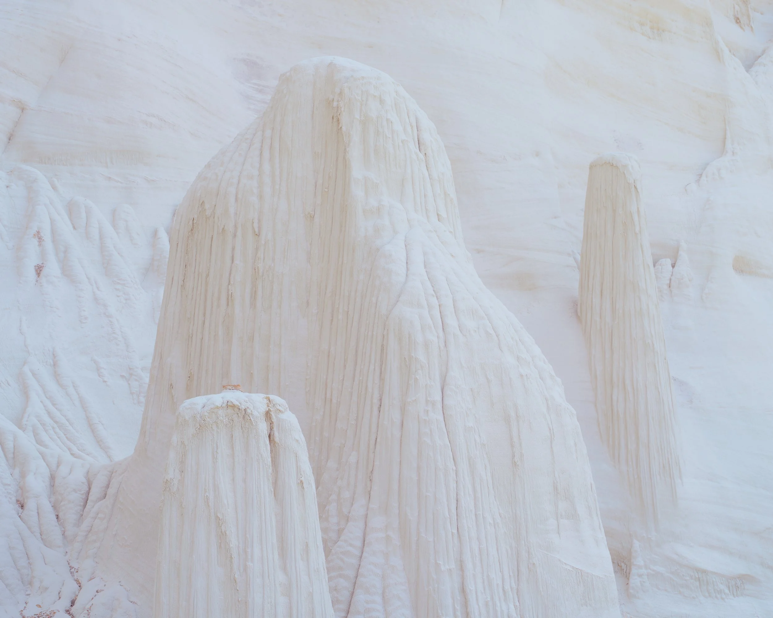 White rock formations resembling towers or stalagmites in a desert or mountain landscape.