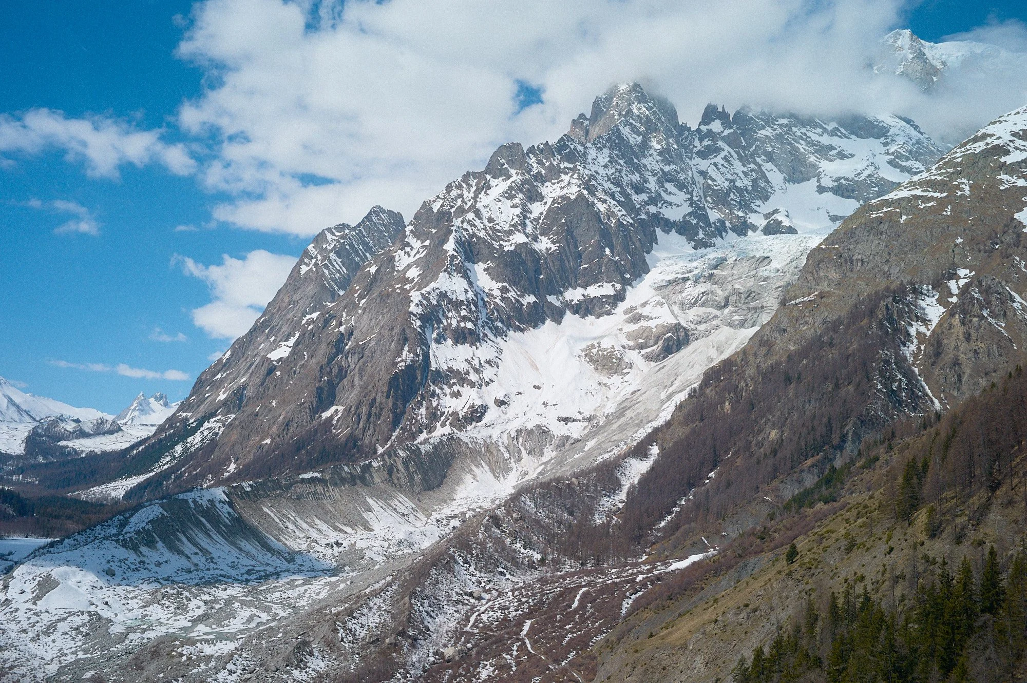 Snow-covered mountain peaks under partly cloudy sky.