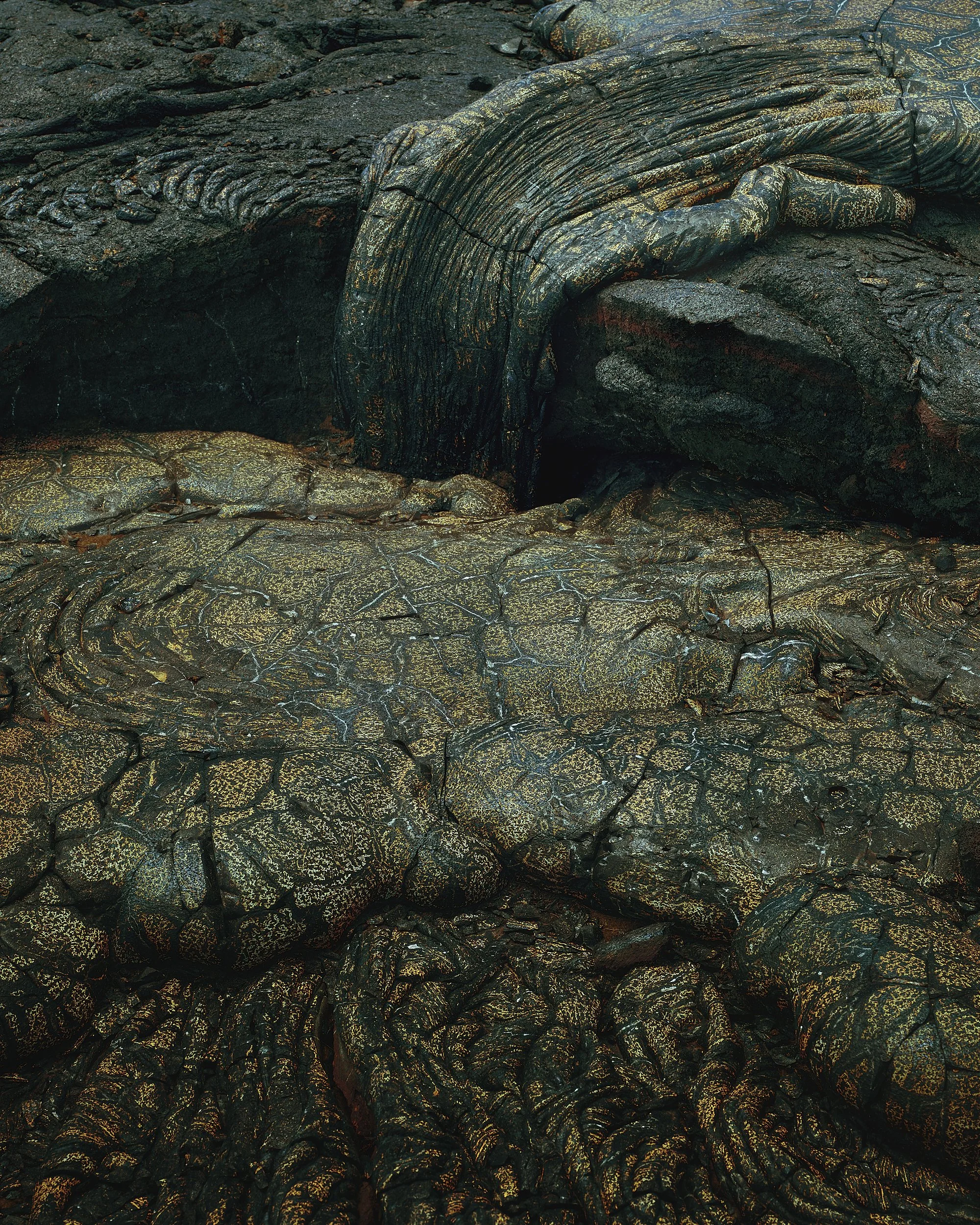Close-up of a volcanic surface with textured, cracked, and hardened lava rocks.