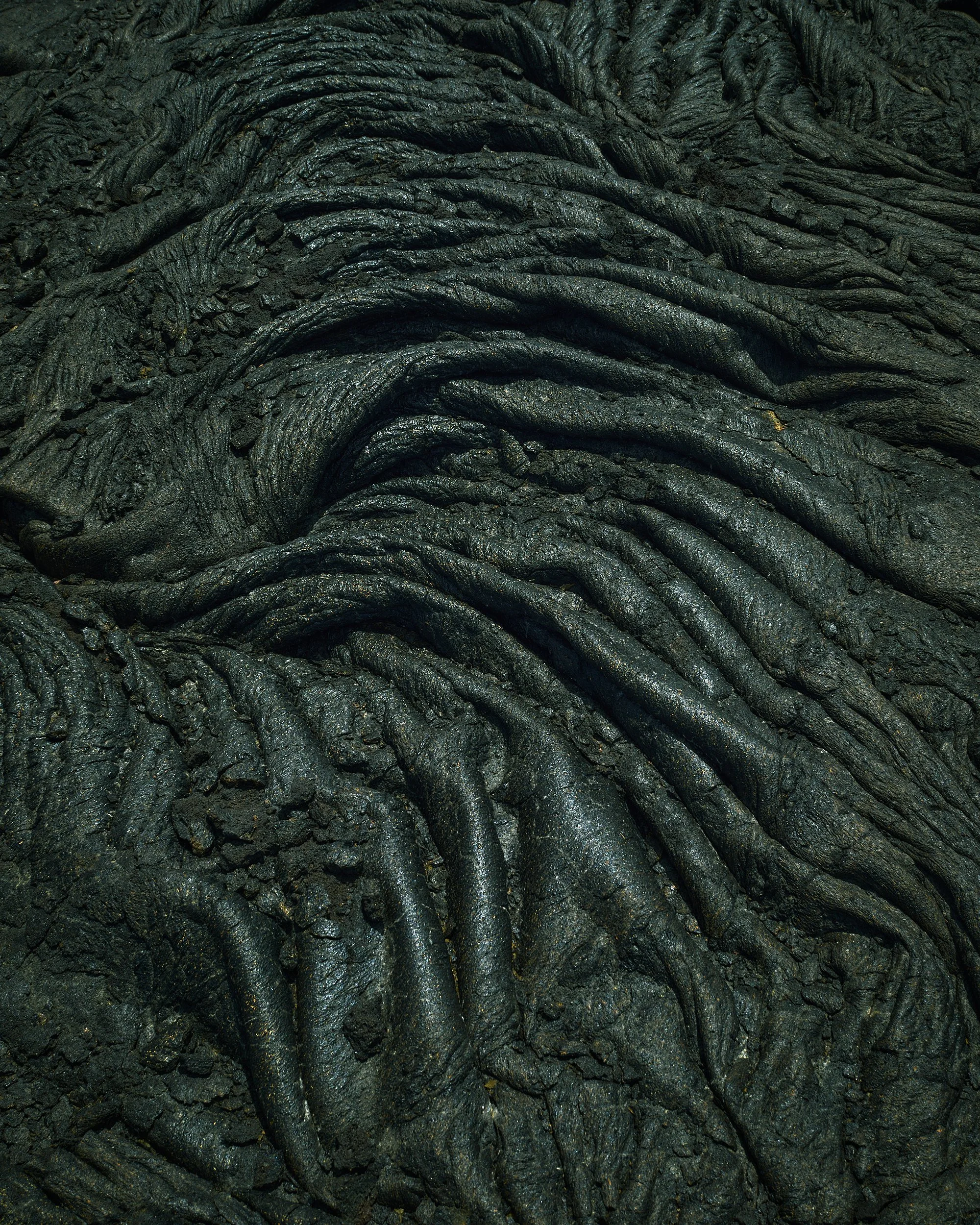 Close-up of rippled, black, volcanic lava rock surface.