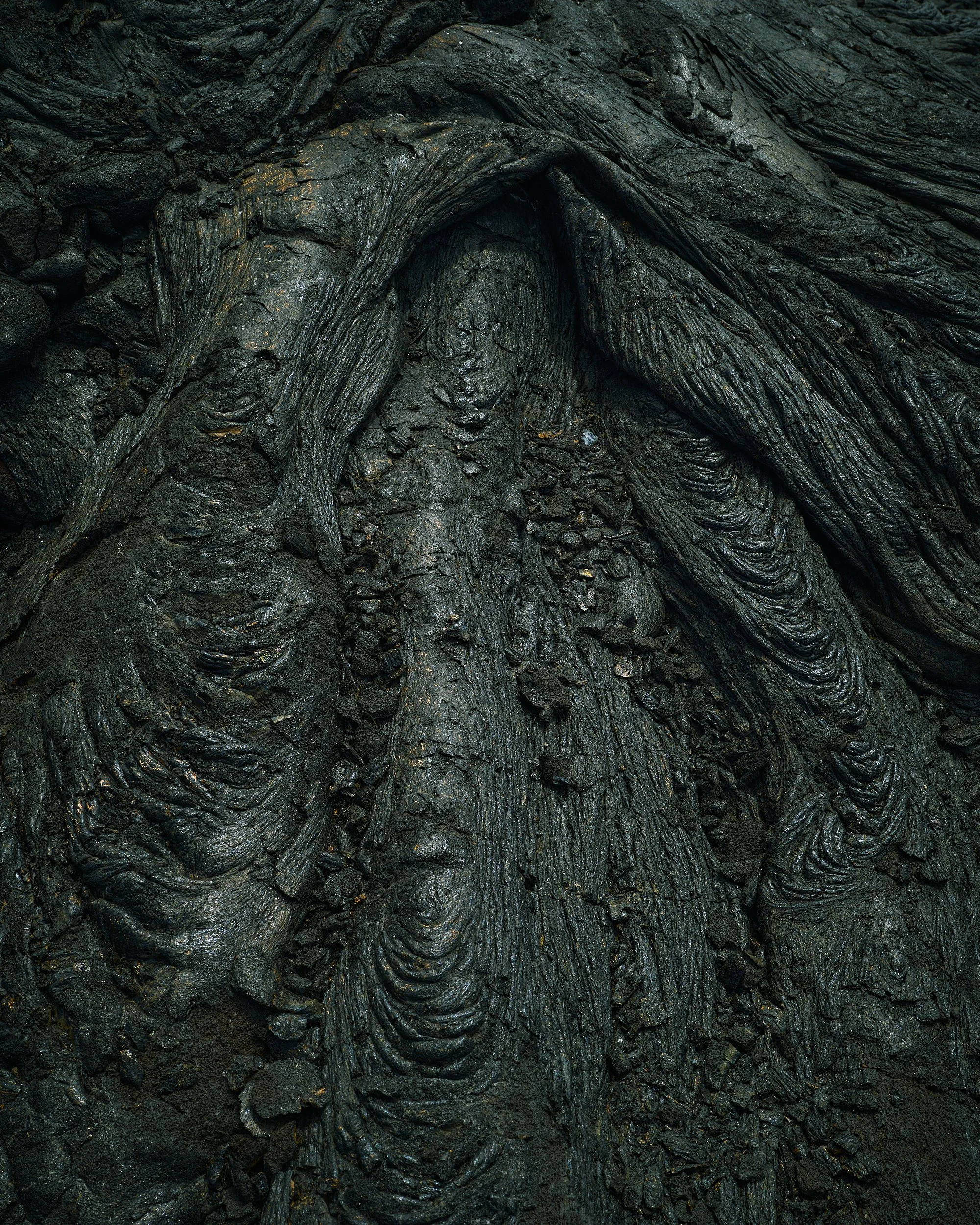 Close-up of dark, textured, layered volcanic rock formations.