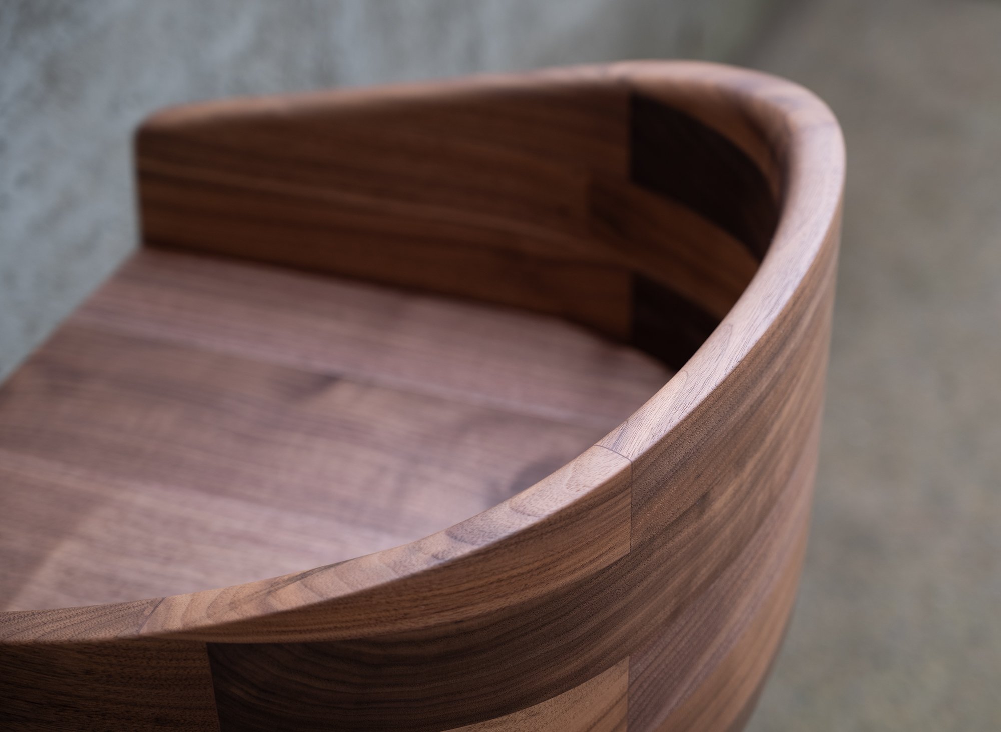 Close-up of a curved wooden chair with a smooth finish.