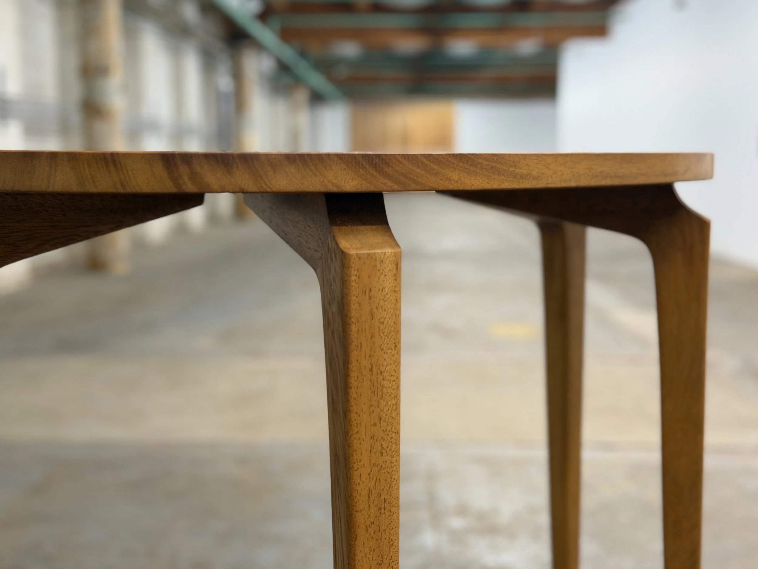 Close-up of a wooden table leg and part of the tabletop in a workshop or storage area.