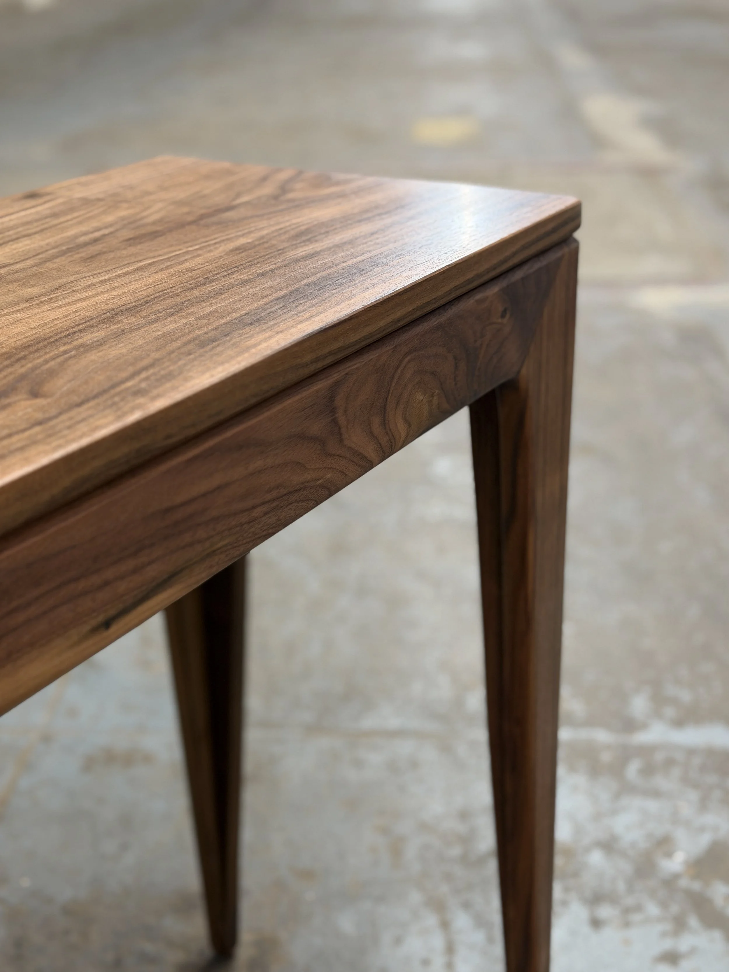 Close-up of a wooden piece of furniture, possibly a table or cabinet, showing the wood grain and smooth finish.