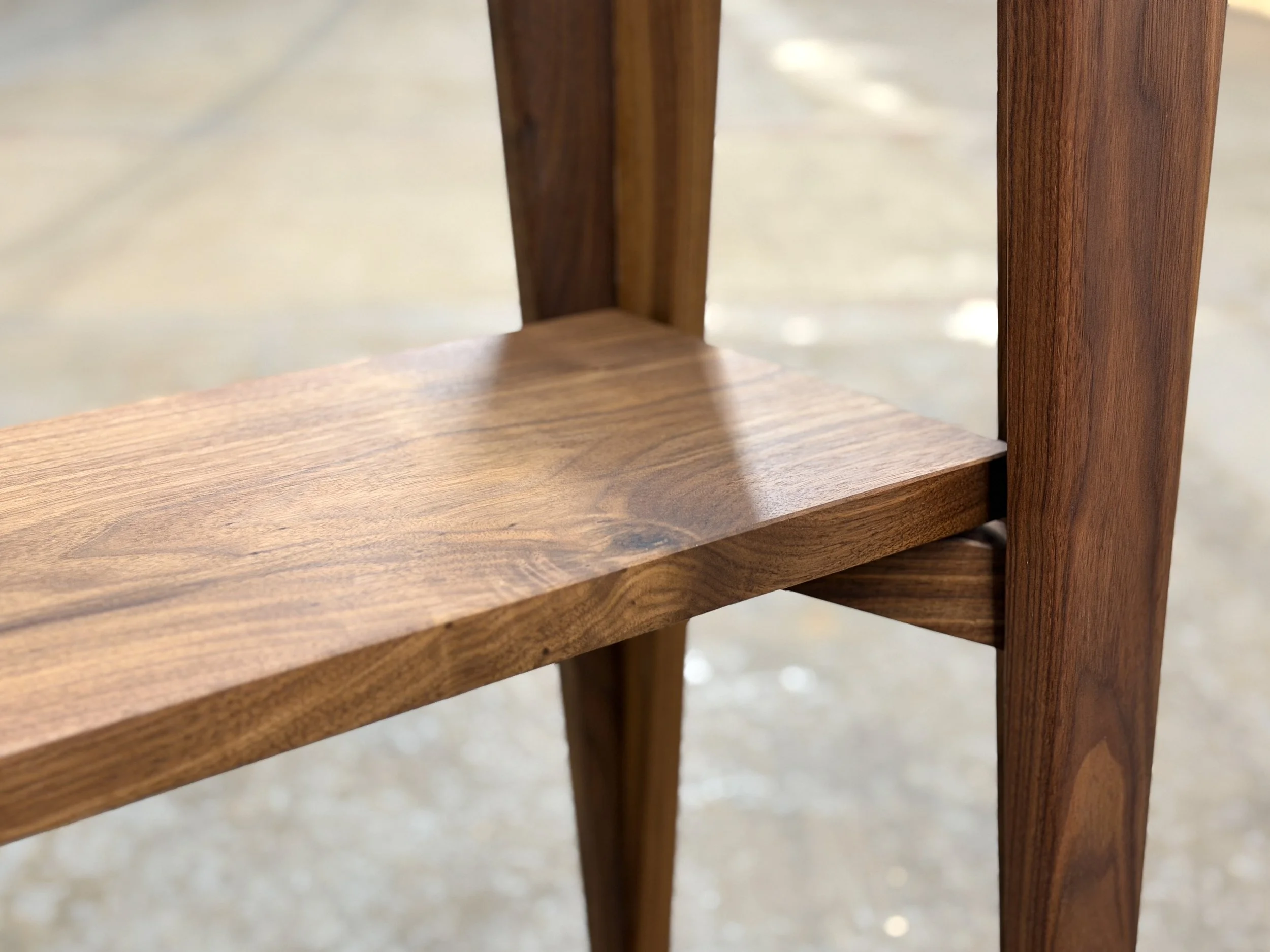 Close-up of a wooden table leg and shelf, showcasing the wood grain and joinery.