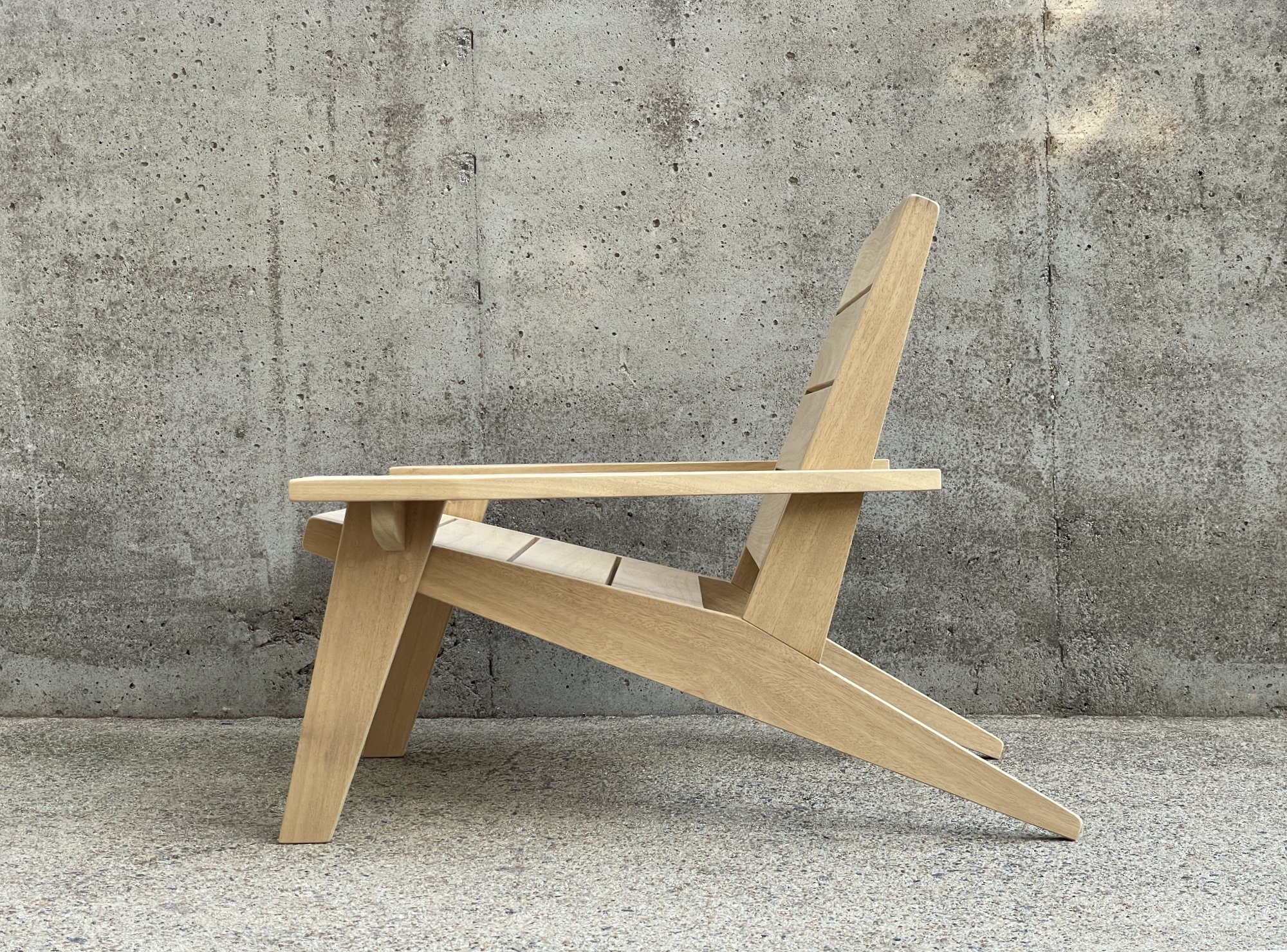 wooden chair with arms set against a concrete wall outside