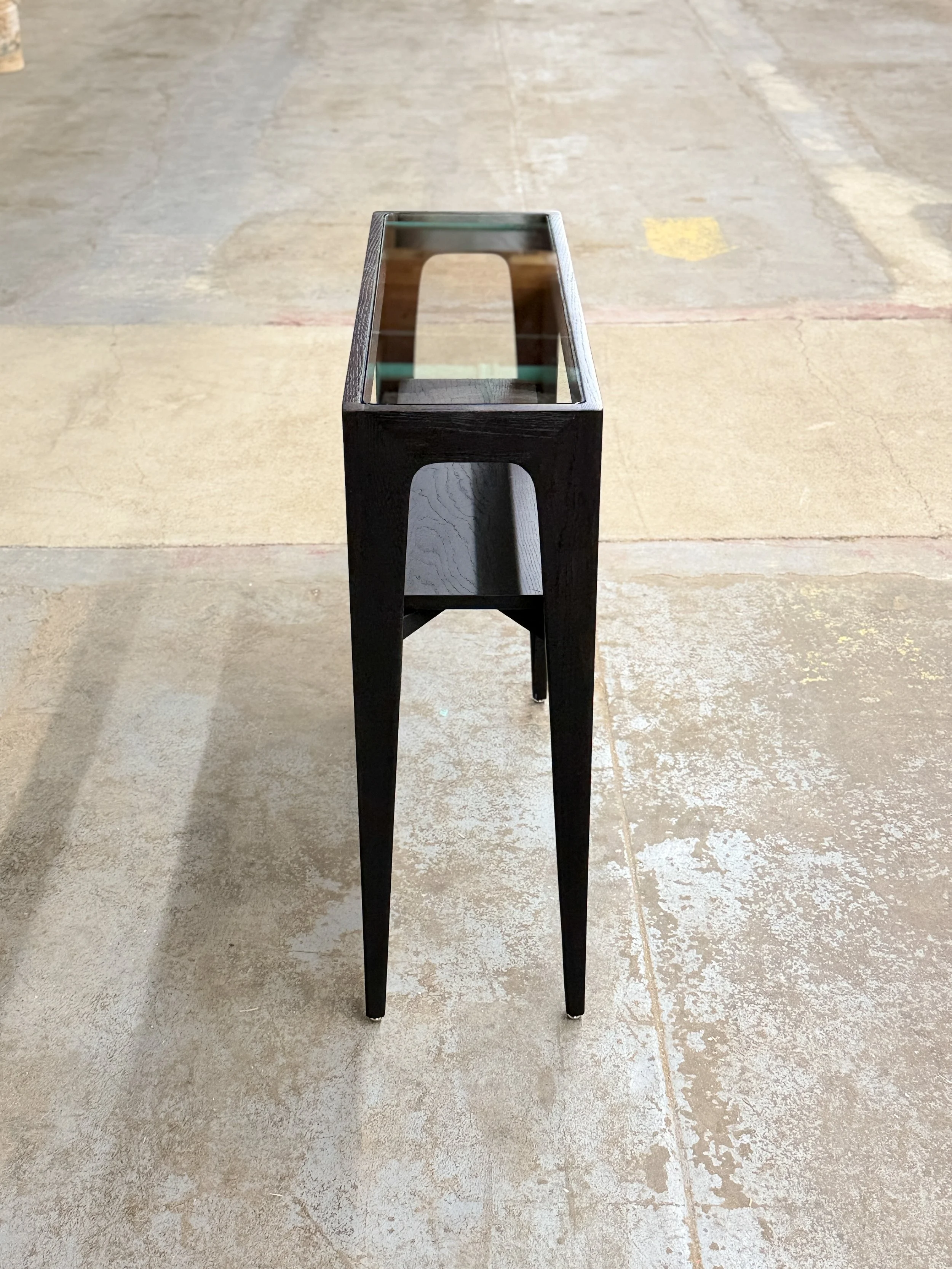 A black wooden and table with four legs, positioned on a concrete floor.