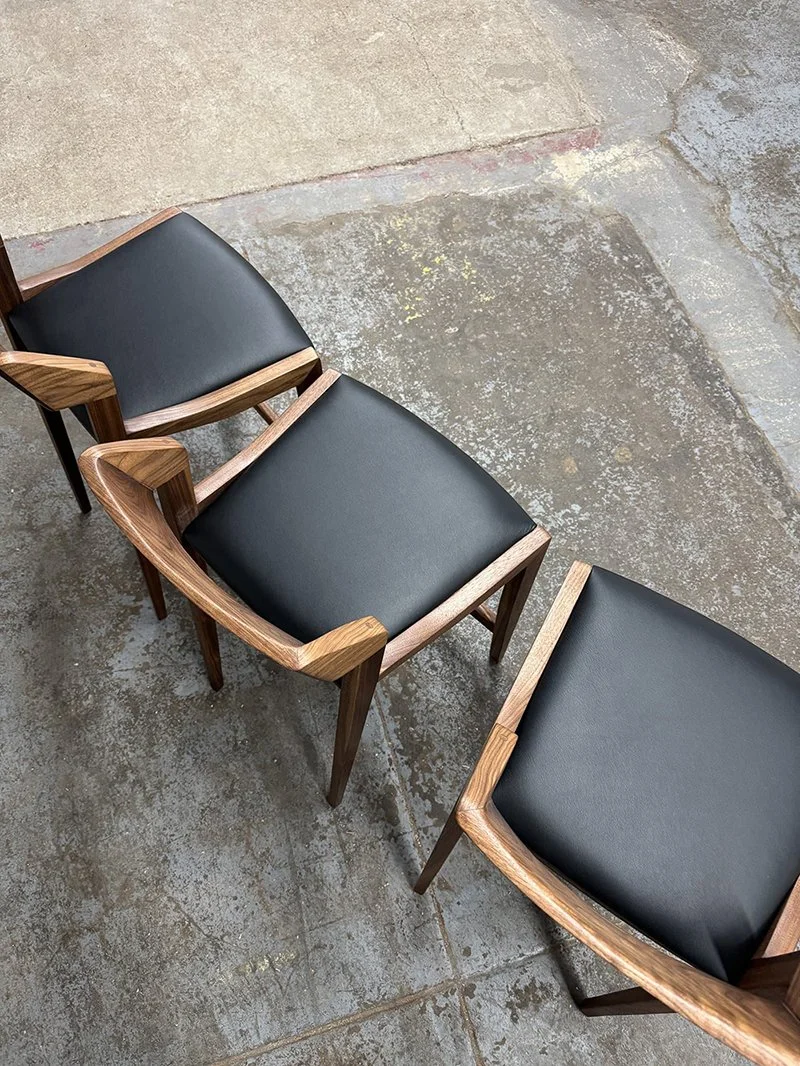 aerial view of 3 chairs with wood frames and black leather cushions