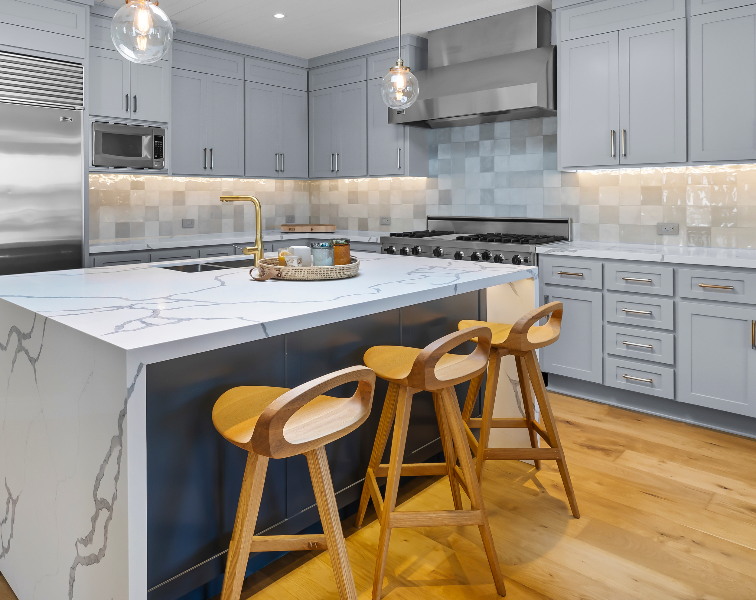 modern kitchen with marble counter and three wood stools